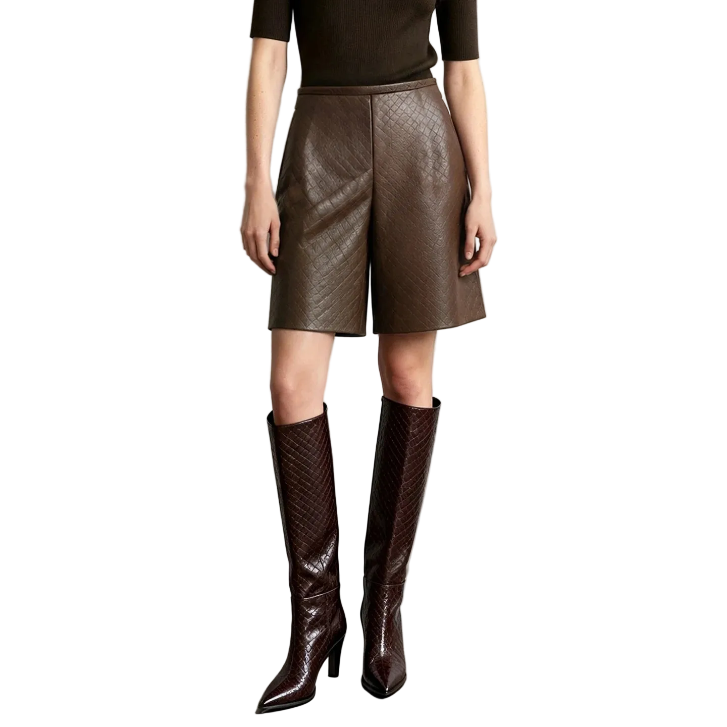 A model wearing AMII brown textured faux-leather shorts and matching dark brown knee-high boots, standing against a light gray wall.