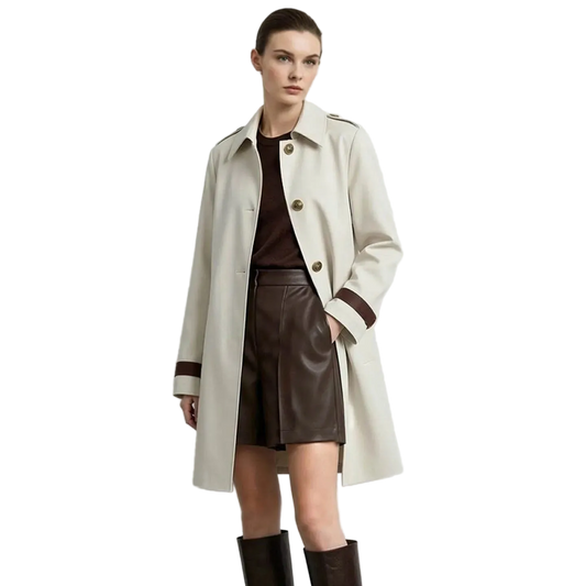 A model wearing a light beige trench coat with brown trim over a dark brown top and skirt, paired with dark brown knee-high boots. The AMII brand logo is visible in the top left corner against a plain light gray background.