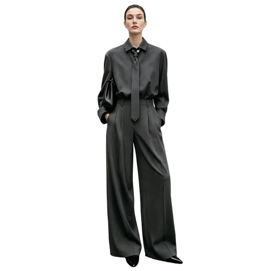 A model stands against a textured gray wall wearing an AMII dark gray long-sleeve button-up shirt with a matching tie and wide-leg trousers, paired with black pointed shoes.