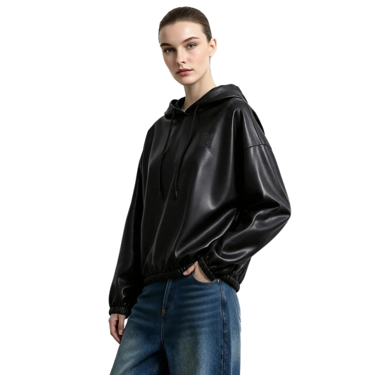 A woman modeling a black faux-leather hooded sweatshirt with drawstrings and elastic cuffs, paired with blue jeans, against a light gray studio background. The brand name AMII is printed in the top left corner.