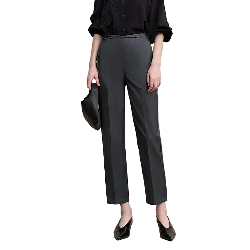 A model wearing AMII dark gray wide-leg cropped trousers, paired with a black blouse, black pointed shoes, and holding a black handbag, set against a plain beige studio background.