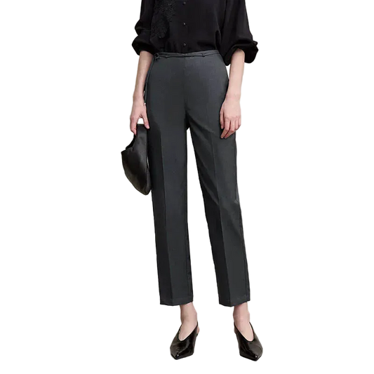 A model wearing AMII dark gray wide-leg cropped trousers, paired with a black blouse, black pointed shoes, and holding a black handbag, set against a plain beige studio background.