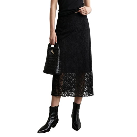 A model wearing a black lace midi skirt with a solid black overlay, paired with black leather ankle boots and holding a black woven handbag. The AMII brand logo is visible in the top left corner against a neutral gray studio background.