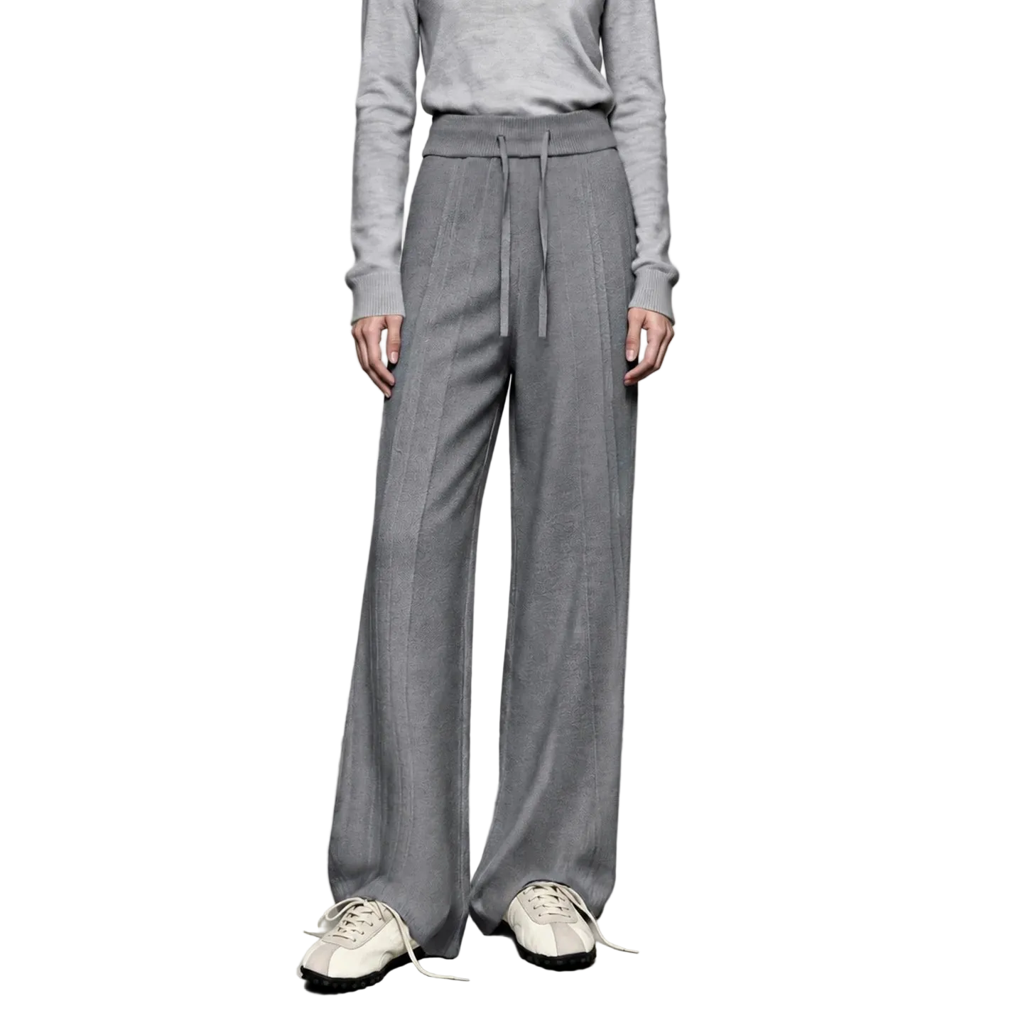 A model wearing AMII gray wide-leg knit pants with a drawstring waist, paired with a matching gray long-sleeve top and white sneakers, set against a minimalist studio background.