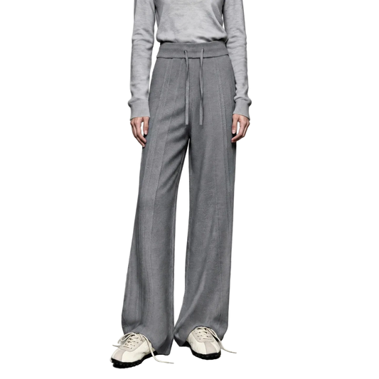 A model wearing AMII gray wide-leg knit pants with a drawstring waist, paired with a matching gray long-sleeve top and white sneakers, set against a minimalist studio background.