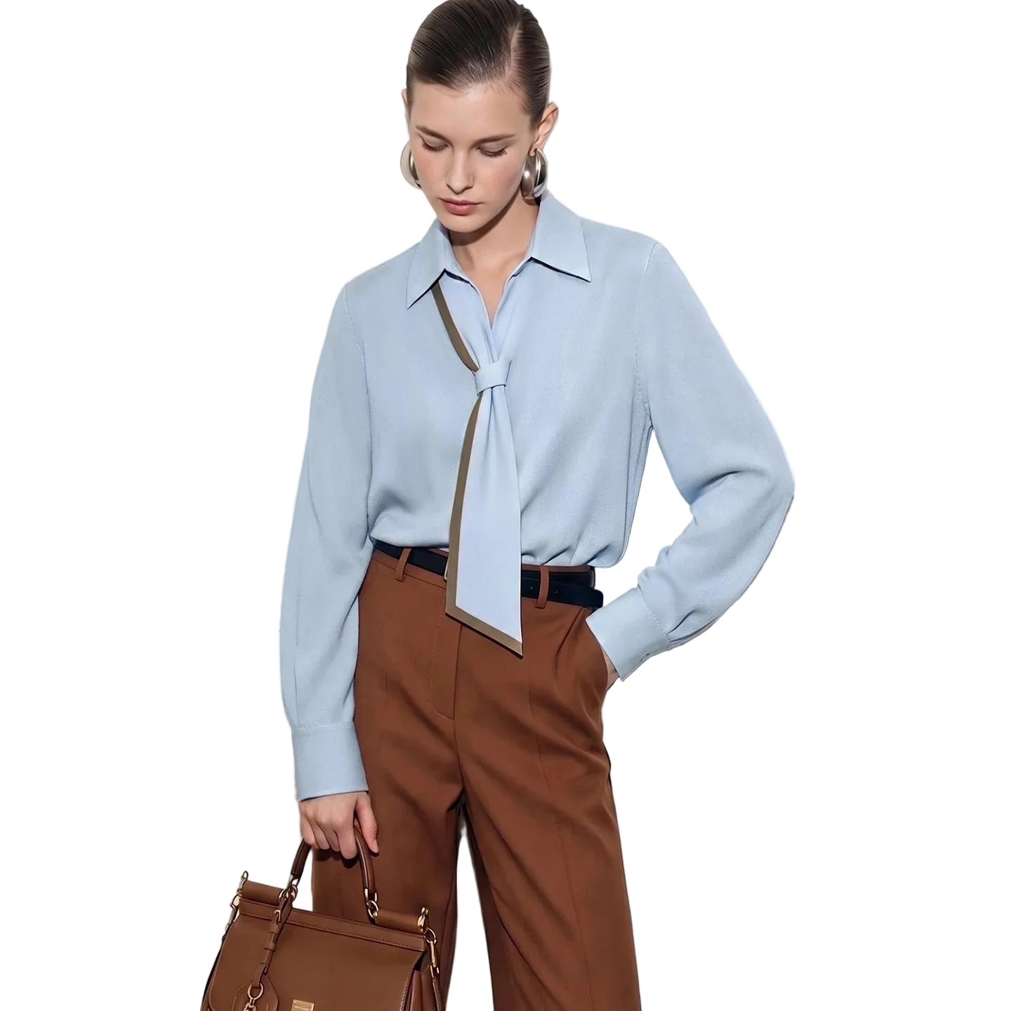 A woman models a light blue long-sleeve blouse with a tie-neck detail, paired with brown trousers and holding a brown handbag, set against a white paneled door. The brand name AMII is visible in the top left corner.