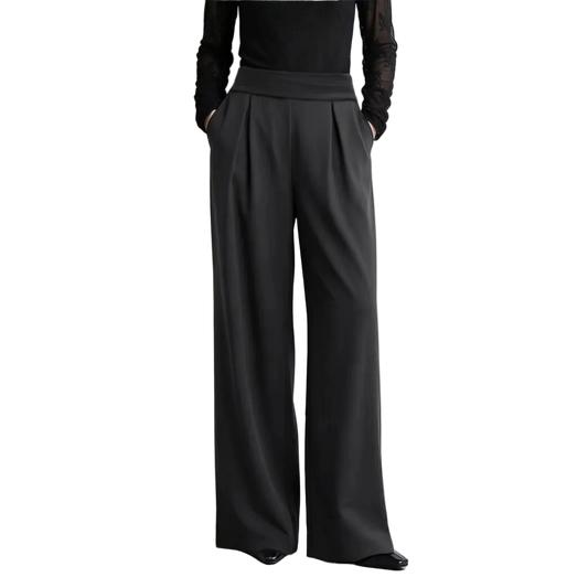 A model from the chest down wearing black wide-leg trousers with a matching black long-sleeve top, standing against a light gray wall. The AMII brand logo is visible in the top left, along with a text callout about wrinkle-resistant fabric.
